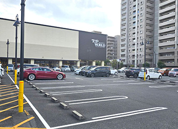 お車でお越しの際はタイムズトップワールド香里ケ丘店をご利用ください。駐車後は、1階店内入口方向へ進みます